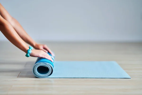 Ung kvinna rullande yoga matta hemma — Stockfoto