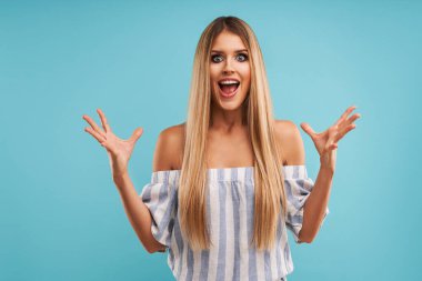 Güzel yetişkin kadın mavi arka planda poz veriyor.