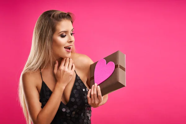 Hermosa mujer adulta posando sobre fondo rosa con presente —  Fotos de Stock