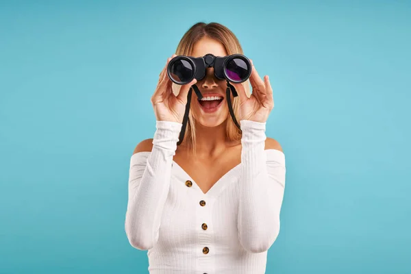 Hermosa mujer adulta posando sobre fondo azul con prismáticos — Foto de Stock