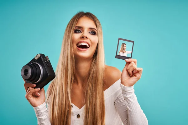 Hermosa mujer adulta posando sobre fondo azul tomando fotos instantáneas —  Fotos de Stock