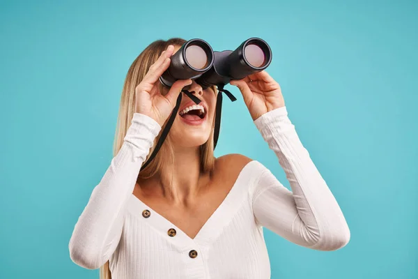 Hermosa mujer adulta posando sobre fondo azul con prismáticos — Foto de Stock