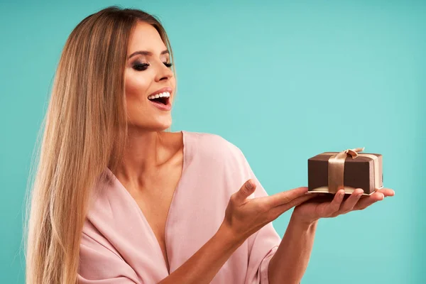 Hermosa mujer adulta posando sobre fondo azul con presente —  Fotos de Stock