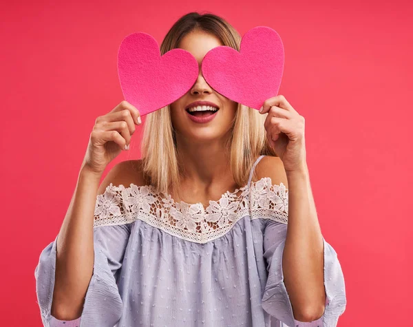 Schöne erwachsene Frau posiert auf rosa Hintergrund mit Herzen — Stockfoto