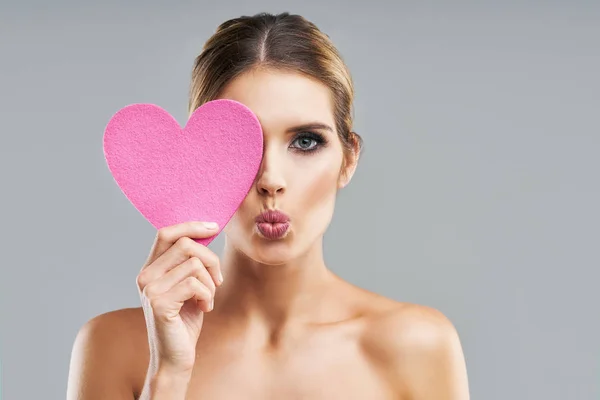 Hermosa mujer adulta posando sobre fondo gris con corazón — Foto de Stock