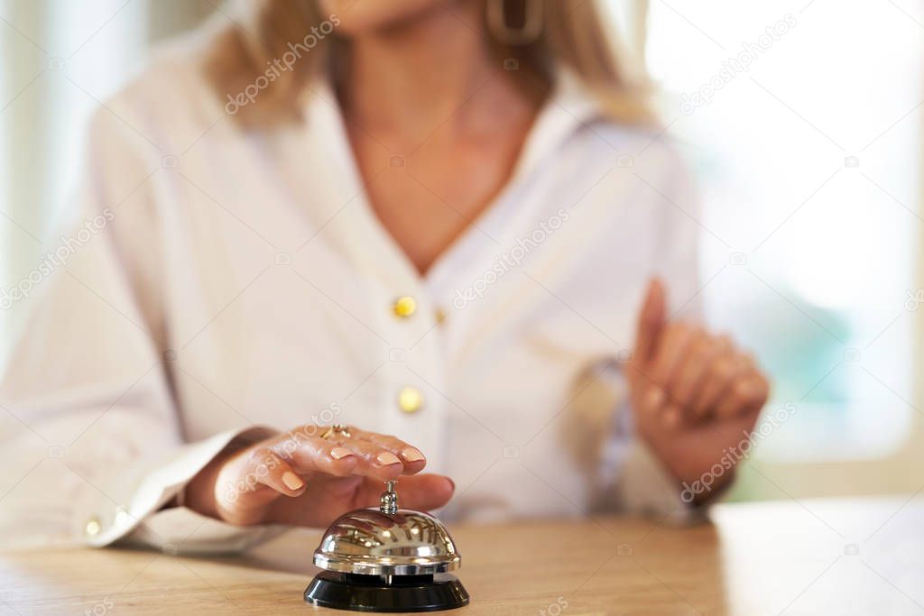 Businesswoman using bell at hotel front desk