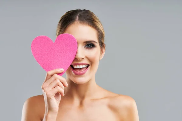 Schöne erwachsene Frau posiert über grauem Hintergrund mit Herz — Stockfoto