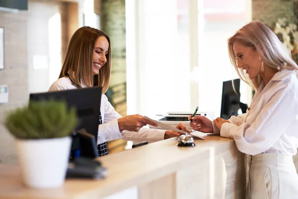 Receptionist and businesswoman at hotel front desk — Stock Photo, Image