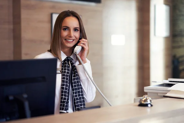 Recepcionista atendendo telefone na recepção do hotel — Fotografia de Stock