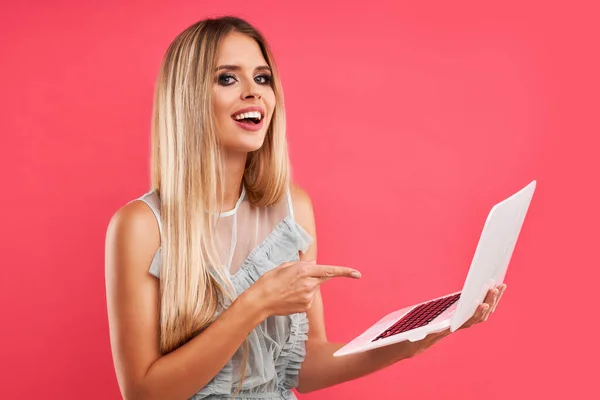 Hermosa mujer adulta posando sobre fondo rosa con computadora —  Fotos de Stock