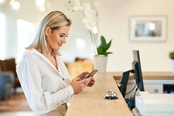 Businesswoman using smartphone at hotel front desk