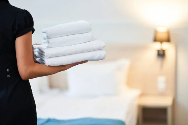 Empregada com toalhas frescas no quarto de hotel — Fotografia de Stock