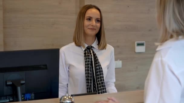 Recepciós asszisztens a szálloda vendége az íróasztalnál — Stock videók