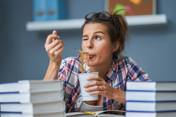 Hungry student eating noodle while learning at home — Stock Photo, Image