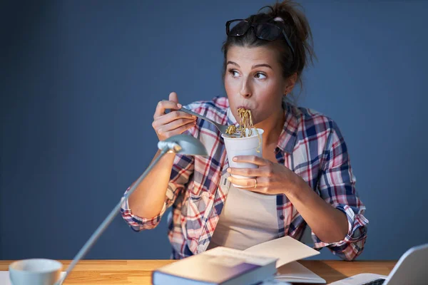 家で学びながら麺を食べる空腹の学生 — ストック写真