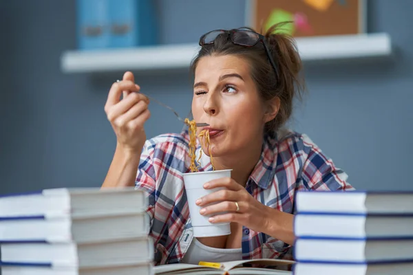 Hongerige student die noedels eet terwijl hij thuis leert — Stockfoto