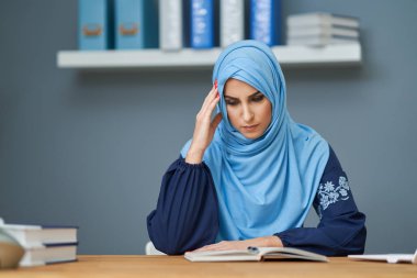 Unhappy muslim female student learning at home
