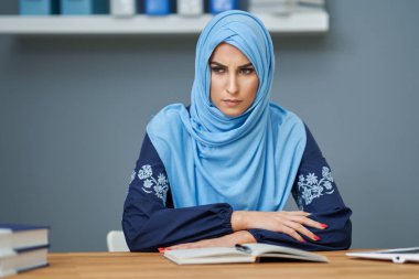 Unhappy muslim female student learning at home