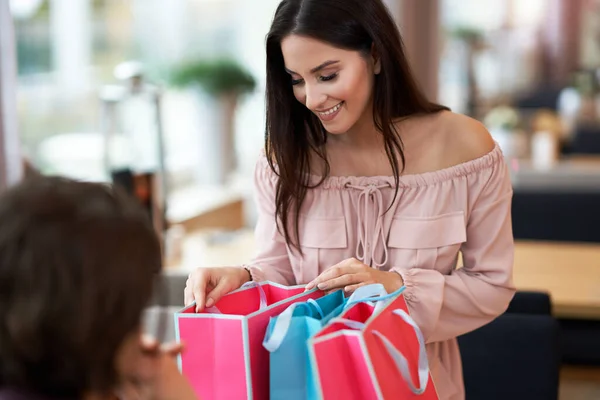 Mujer feliz con bolsas de compras conociendo a alguien en el restaurante —  Fotos de Stock