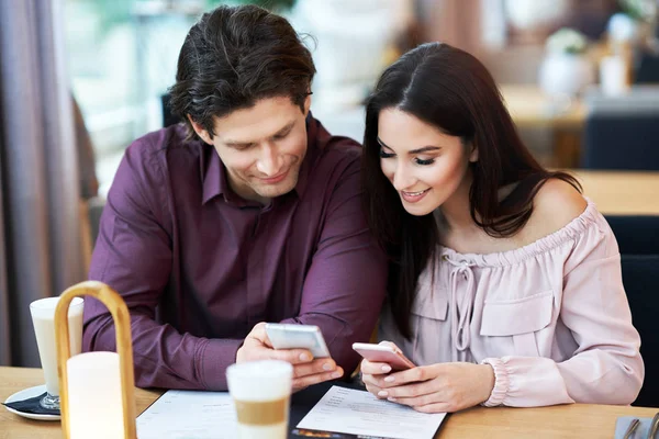 Молодая пара с помощью смартфонов в кафе — стоковое фото