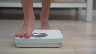 Adult woman checking weight on bathroom scales in the morning