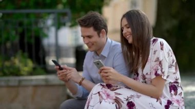 Happy couple spending time outdoors and using smartphone