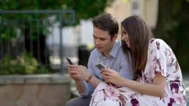Happy couple spending time outdoors and using smartphone