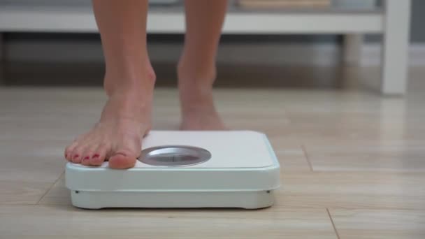 Взрослая женщина проверяет вес на весах в ванной утром — стоковое видео