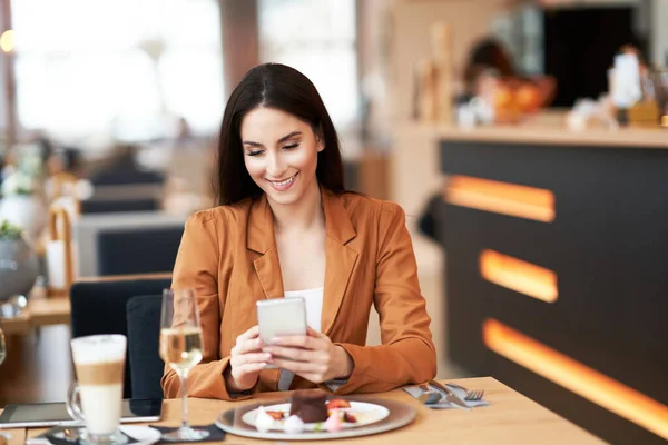 Businesswoman with smartphone at lunch in cafe — Stockfoto