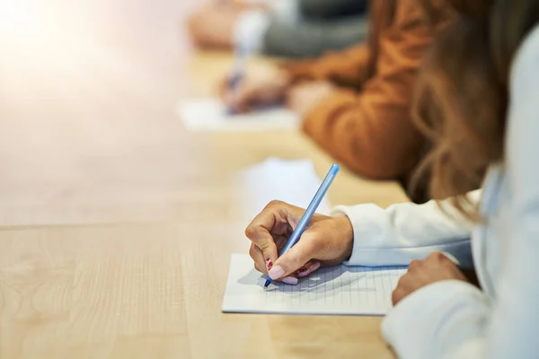 Foto van een menselijke hand die iets op het papier op de voorgrond schrijft — Stockfoto