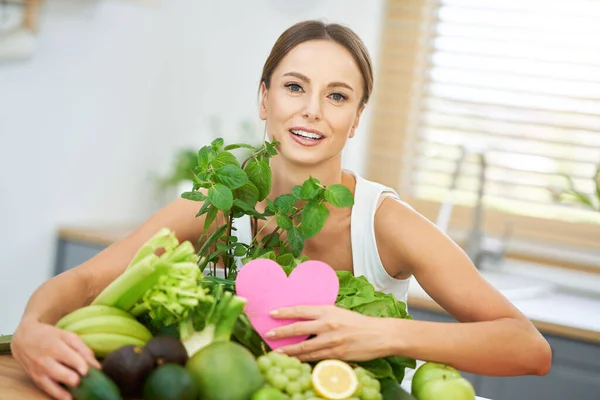 Mujer adulta saludable con comida verde en la cocina — Foto de Stock