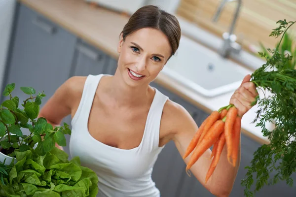 Здоровая взрослая женщина с зеленой пищей на кухне — стоковое фото