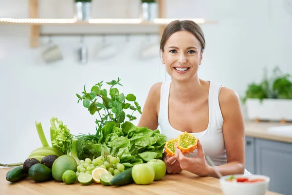 Friska vuxna kvinna med grön mat i köket — Stockfoto