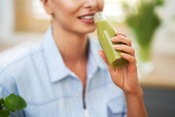 Gezonde volwassen vrouw met groen eten in de keuken — Stockfoto