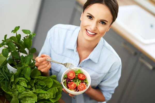 Zdravá dospělá žena se zeleným jídlem v kuchyni — Stock fotografie