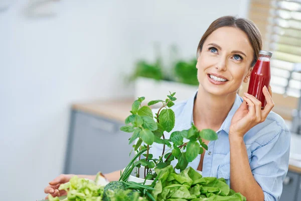 Mulher adulta saudável com comida verde na cozinha — Fotografia de Stock