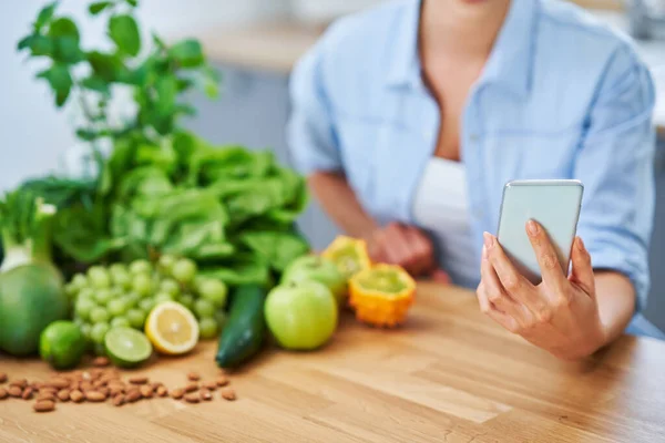 Zdrowa dorosła kobieta z zielonym jedzeniem w kuchni — Zdjęcie stockowe