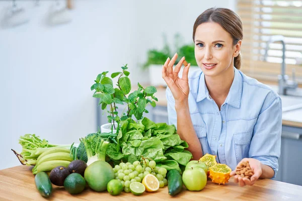 Zdravá dospělá žena se zeleným jídlem v kuchyni — Stock fotografie