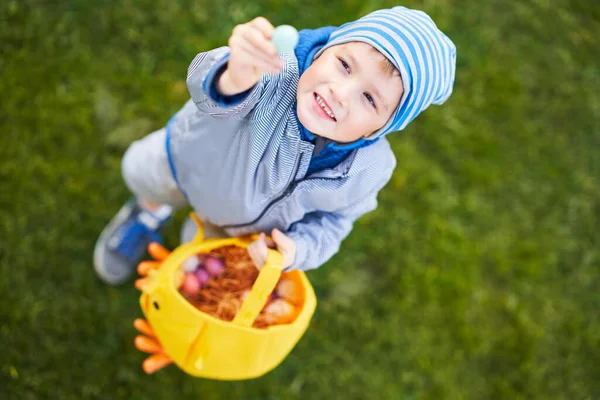 Мальчик в защитной маске охотится за пасхальными яйцами в весеннем саду . — стоковое фото
