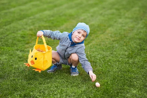 Malý chlapec nosí ochranné masky lov na velikonoční vejce na jarní zahradě. — Stock fotografie