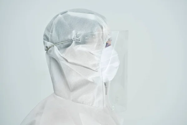 Mujer en traje de bio-peligro y escudo facial sobre fondo blanco . — Foto de Stock