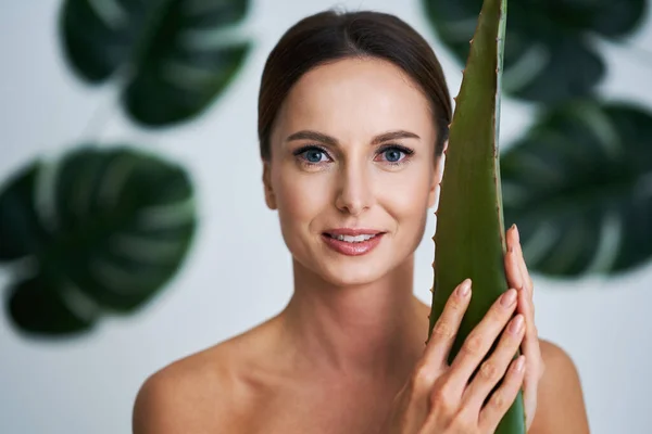 Mooie volwassen vrouw poseren tegen blad achtergrond — Stockfoto