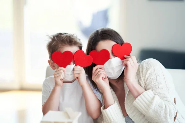 Mère et son fils à la maison en quarantaine pendant la pandémie de coronavirus tenant les coeurs — Photo