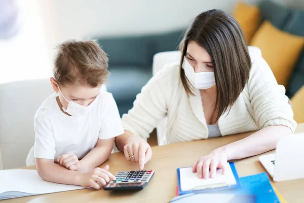 Jongen en uitgeputte moeder probeert thuis te werken tijdens een coronavirus pandemie — Stockfoto