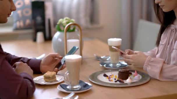 Restoranda flört eden ve akıllı telefon kullanan genç bir çift. — Stok video