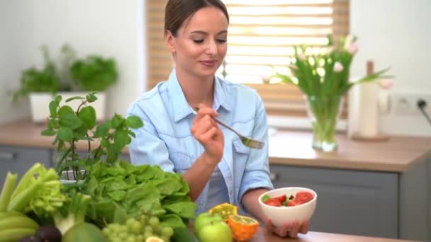 Mulher feliz comendo salada enquanto sentado em sua cozinha — Vídeo de Stock