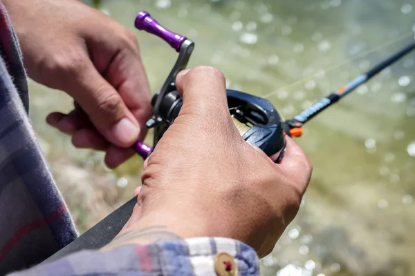 Carrete de baitcasting en la mano del pescador —  Fotos de Stock