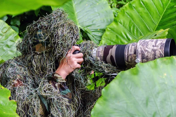 Fotógrafo de vida selvagem camuflagem no terno ghillie trabalhando na natureza Fotografia De Stock