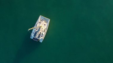 İnsansız hava aracı, sakin bir körfeze demirlemiş katamaran yelkenlilerinin yüksek açılı görüntüsünü yakalıyor..