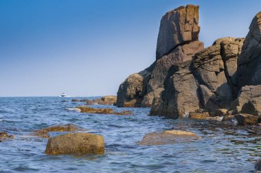 Mavi gökyüzüne karşı kayalık deniz kıyısı